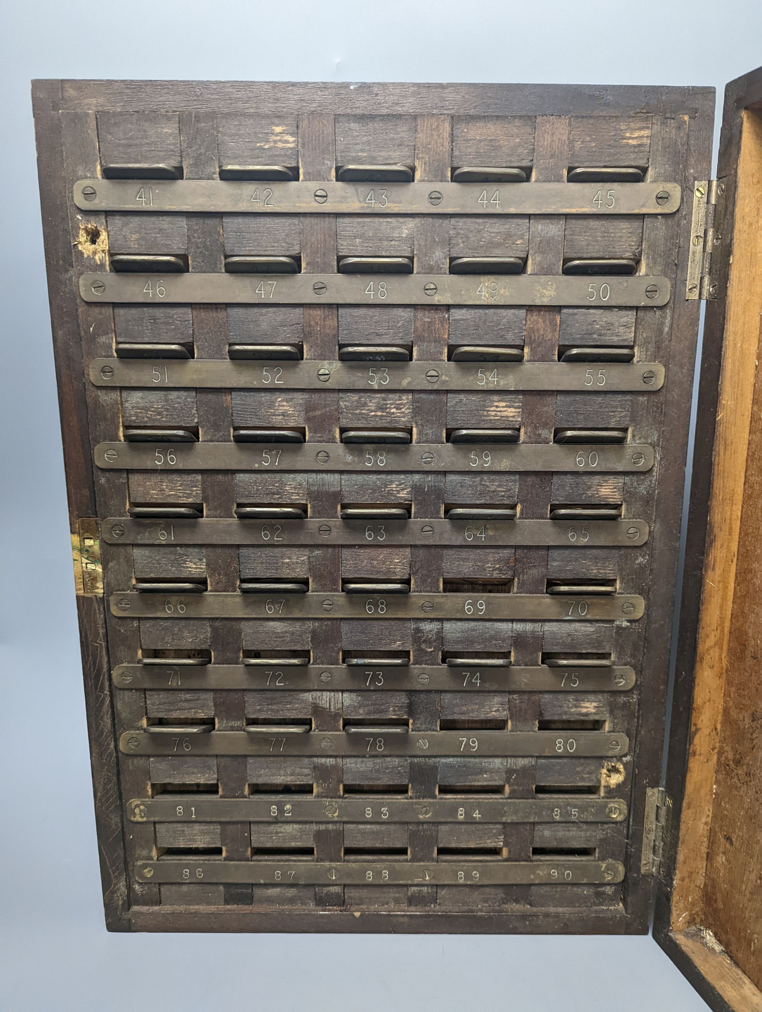 An early 20th century textile mill clocking in board with engraved numbered tokens